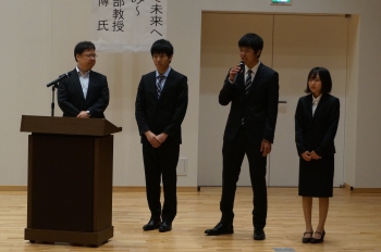 取組について説明する田中教授と代表の企業情報学部の学生