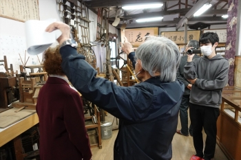 道具の解説をする地元の方、撮影をする学生