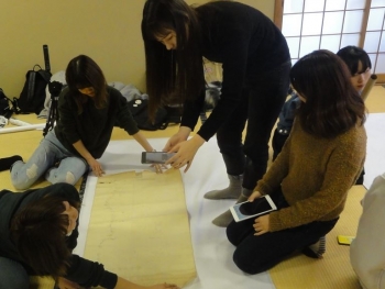 学生が古い資料を撮影している作業風景