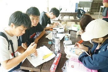 ご飯を炊くための空き缶を加工する学生たち